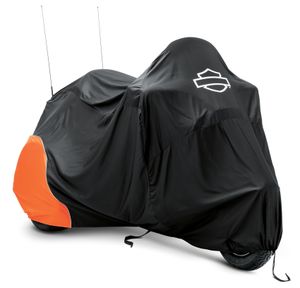 Harley-Davidson Accessories Pamper your bike. This luxuriously soft microfiber cover is ideal for short and long term indoor storage. - The breathable microfiber material promotes air circulation to reduce moisture build-up and minimize corrosion - Cover skirt features front and rear adjustable drawstrings to cinch the cover around the bike, and a convenient belly strap to reduce ballooning in the wind - The corset-style cinching system along the backbone lets you adjust the cover for best fit on a variety of models - The cover features heat-resistant panels that protect the material from warm exhaust, and the hook-and-loop opening at the rear of Touring and Trike covers accommodates antennas - The two-tone orange and black cover features reflective piping for added visibility, and an integrated storage pouch for convenient packing when not in use