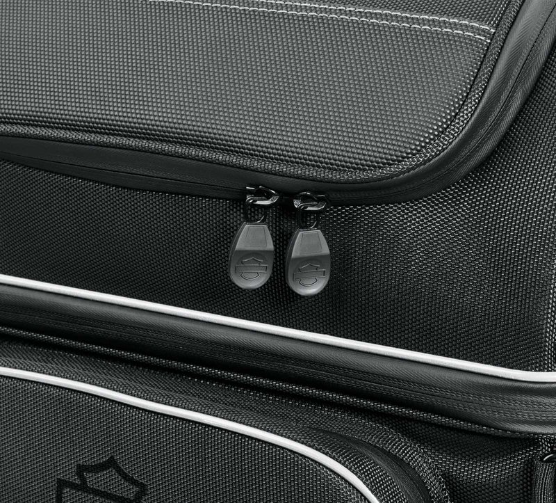 Harley-Davidson Accessories Onyx Premium Touring Bag. Part of the Onyx Premium Luggage Collection, this Touring Bag is built for long-haul trips. It features a separate top compartment to keep your shoes apart from your clothes, a main compartment large enough for two weeks of jeans and t-shirts, and removable lid straps that stop the top compartment falling forward or back when loading. The large front pocket holds keys, pens, documents and small electronics, two upper outer pockets suit eyewear, and two large lower exterior pockets are ideal for rain gear. Made of premium 1680-denier UV-stable ballistic polyester that stands up to tough road and weather conditions without fading. Features water-resistant zippers with glove-friendly pulls, a burnt-orange interior for easy visibility, MOLLE-style webbing for modular pouch attachment, a non-slip abrasion-resistant base and reflective piping. Dimensions: 19.2" W x 12.7" D x 20.5" T. Capacity: 3,500 cubic inches (57 litres). Includes a removable shoulder strap and a rain cover with an elastic hem and barrel-lock mechanism that stays put at highway speeds.