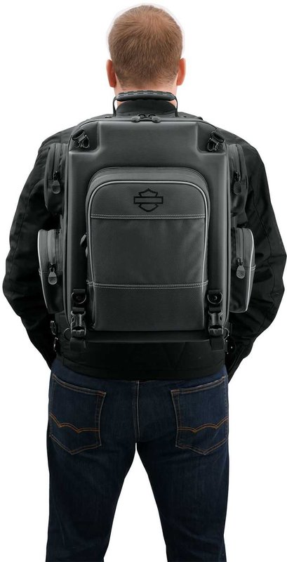 Harley-Davidson Accessories Onyx Premium Luggage Weekender Bag. Part of the Onyx Premium Luggage Collection, this backpack-style Weekender Bag suits around-town use or a weekend getaway. The cavernous main compartment holds a pair of boots, a change of clothes, an extra jacket or sweatshirt and spare gloves and hats. It includes a padded laptop compartment and two further padded pockets for small electronics. Outside there are two pockets (one felt-lined for eyewear), a drawbridge-style front compartment for pens and documents, and four side pockets for chargers, keys and other small items. The mounting straps tuck away into a built-in storage pouch for a clean look, and stowable backpack straps with raised back padding make it comfortable to carry. Made of premium 1680-denier UV-stable ballistic polyester that stands up to tough road and weather conditions without fading. Features water-resistant zippers with glove-friendly pulls, a burnt-orange interior for easy visibility, MOLLE-style webbing for modular pouch attachment, a non-slip abrasion-resistant base and reflective piping. Dimensions: 18" W x 11.5" D x 18" T. Capacity: 1,800 cubic inches. Includes a rain cover with an elastic hem and barrel-lock mechanism that stays put at highway speeds.