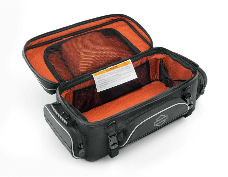 Harley-Davidson Accessories Onyx Premium Luggage Tour-Pak Rack Bag. Part of the Onyx Premium Luggage Collection, this bag is designed to sit atop most Tour-Pak luggage racks, adding storage for long trips. The main compartment features three mesh pockets for organisation and enough space for clothes on a short trip. Outside, the top zip pocket is fleece-lined for protective eyewear storage, while the front, back and side pockets suit gloves, keys, cords and a phone charger. Dual side-carry handles, a rubber top handle and a detachable shoulder strap make off-bike transport easy, and rigid construction keeps the bag in shape even when empty. Made of premium 1680-denier UV-stable ballistic polyester that stands up to tough road and weather conditions without fading. Features water-resistant zippers with glove-friendly pulls, a burnt-orange interior for easy visibility, MOLLE-style webbing for modular pouch attachment, a non-slip abrasion-resistant base and reflective piping. Dimensions: 24" W x 14" D x 10.4" T. Capacity: 2,600 cubic inches (42 litres). Includes a removable shoulder strap and a rain cover with an elastic hem and barrel-lock mechanism that stays put at highway speeds. Fits models equipped with Tour-Pak luggage racks (except FLRT and FLHXXX, or Mini Rack P/N 53100-96).