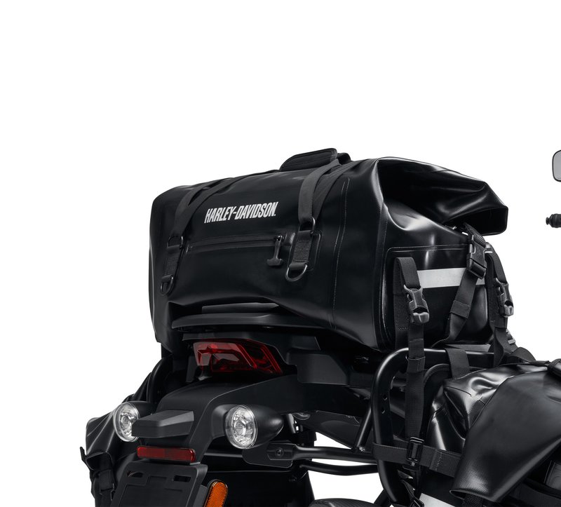 Harley-Davidson Accessories Adventure Duffel Bag. Intended for the hardcore off-road rider, this durable bag is designed for motorcycle use and resists damage if the bike tips over. The material is waterproof, the exterior pockets have waterproof zippers, and the roll-top closure creates a weather-tight seal so your gear stays dry in any conditions. The roll-top design and multiple compression straps let you cinch the load tightly for flexible capacity, and the bag is reflective for visibility in low light. The duffel can be secured to the Top Case Mounting Plate (sold separately) behind the seat, or on the passenger pillion in front of a hard case. Luggage capacity: 2,440 cubic inches (40 litres). Weight capacity: 22 lbs (10 kg). Size: 21" x 12" x 10". Includes universal mounting straps. Fits Pan America RA1250/S '21-later, and universal fitment.